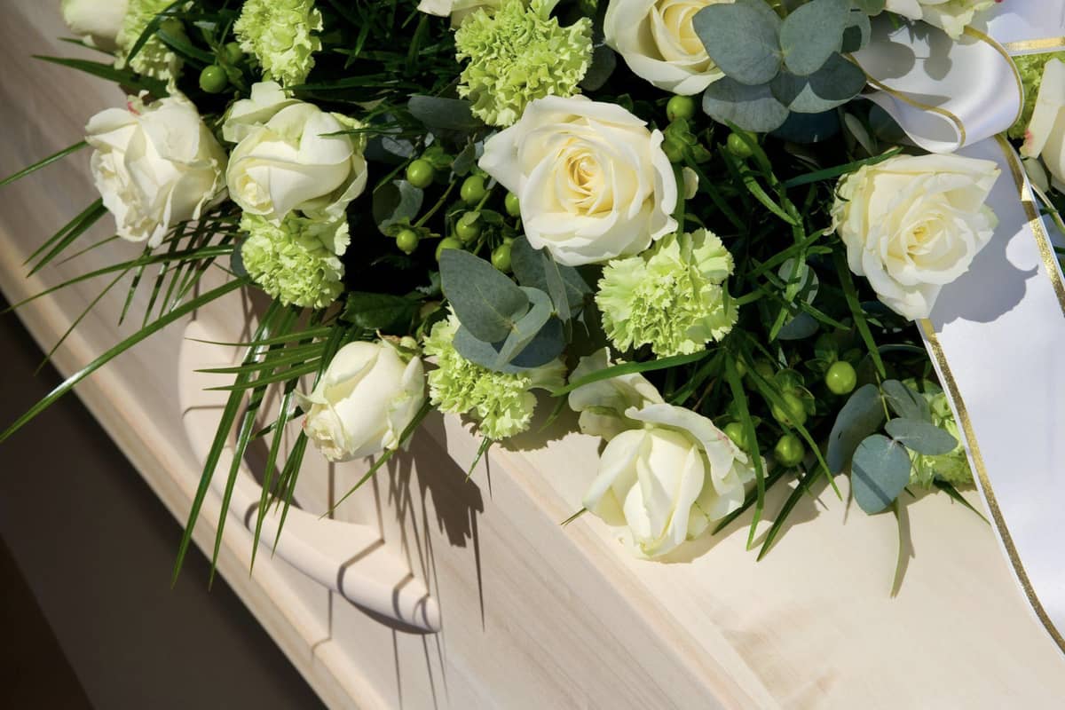 Flowers on top of a white casket