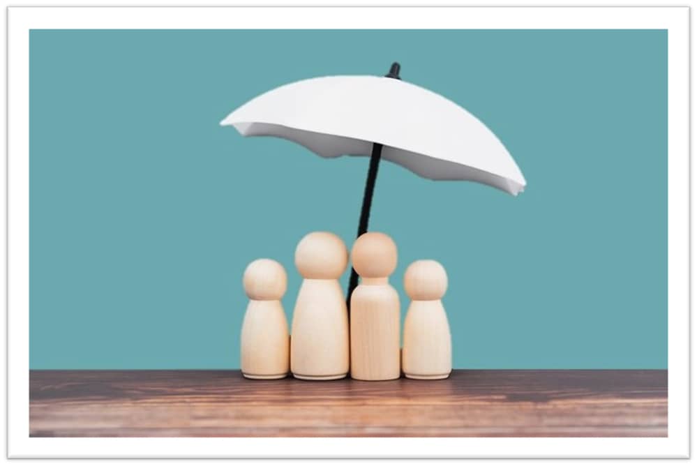 Tiny wooden "people" under a small umbrella
