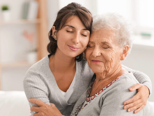 A woman hugging another older woman (presumably her mother)