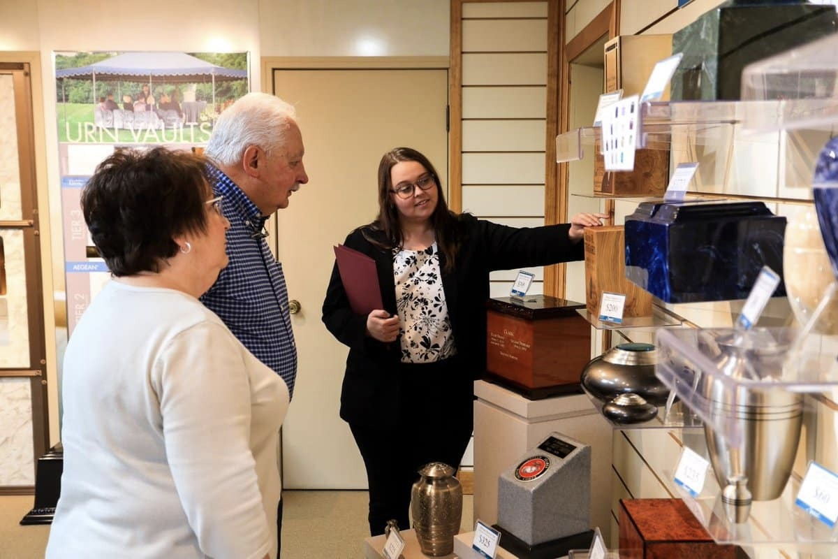 A woman showing a senior couple different urn options