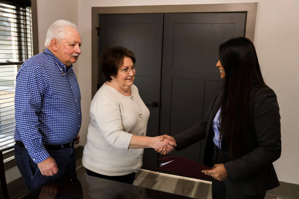 Female employee greeting senior man and woman