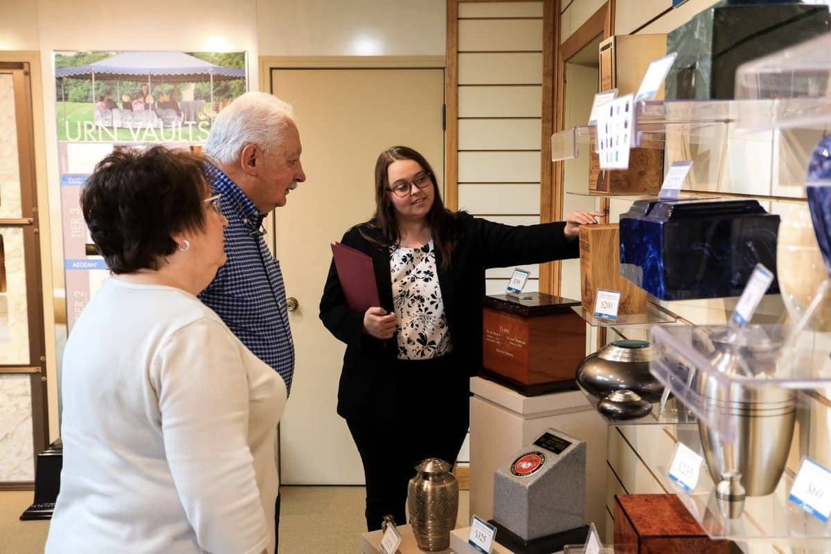 A Sunset employee showing 2 seniors urn options